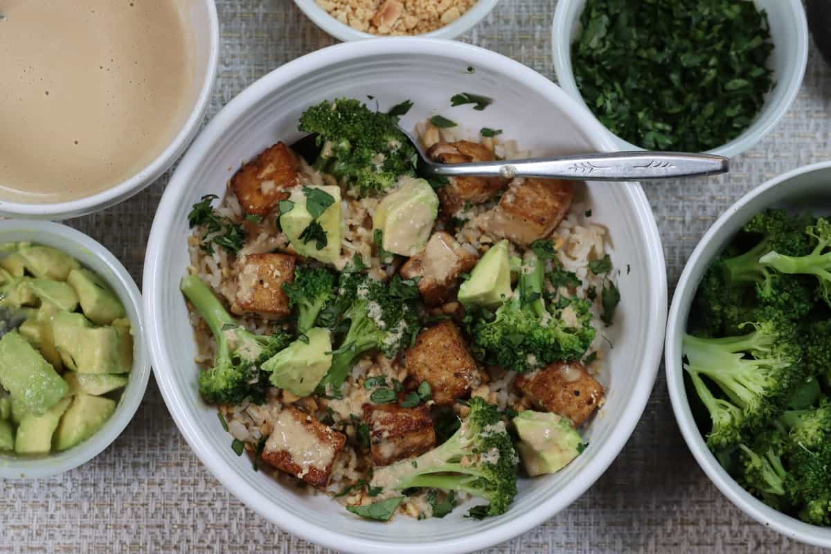 overhead view of a bowl of tofu and broccoli stir fry with soy tahini sauce
