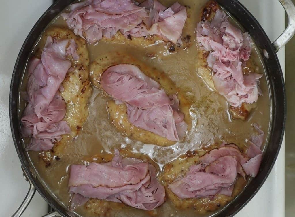 chicken in the sauce with ham slices on top