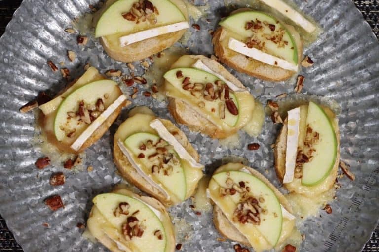 birds eye view of platter of apple brie crostini with pecans and honey drizzle