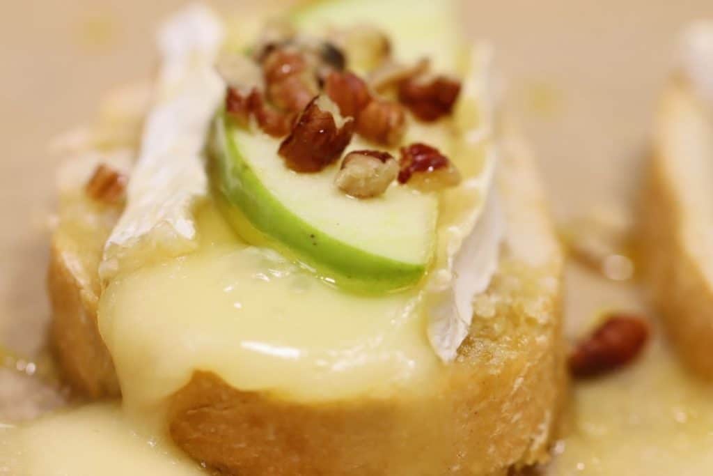 oozy melty brie falling off crostini with apples pecans and honey