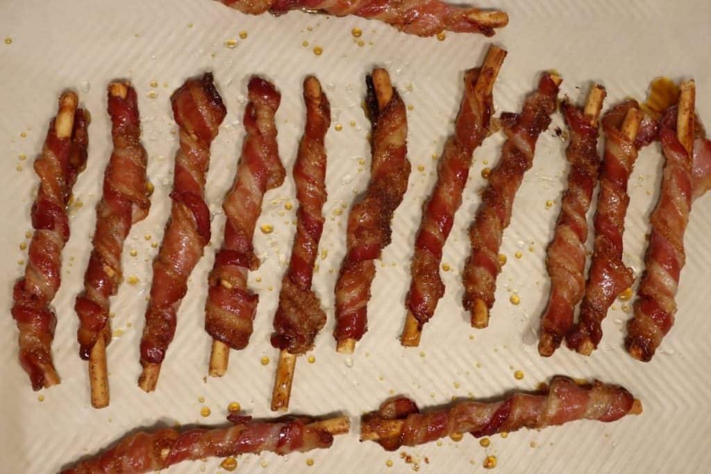 candied bacon sticks on a sheet pan drizzled with maple syrup