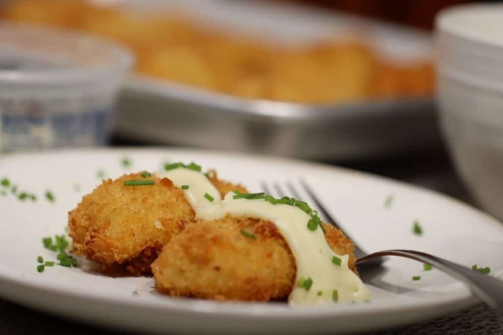 side view of a plate with two potato bacon croquettes with gorgonzola bechamel sauce