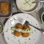 birds eye view of a plate with two potato bacon croquettes with gorgonzola bechamel sauce