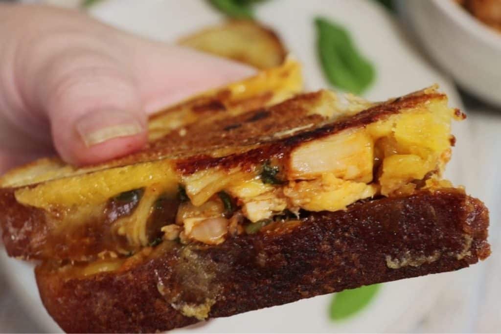 side view of bbq chicken panini with cheddar and basil