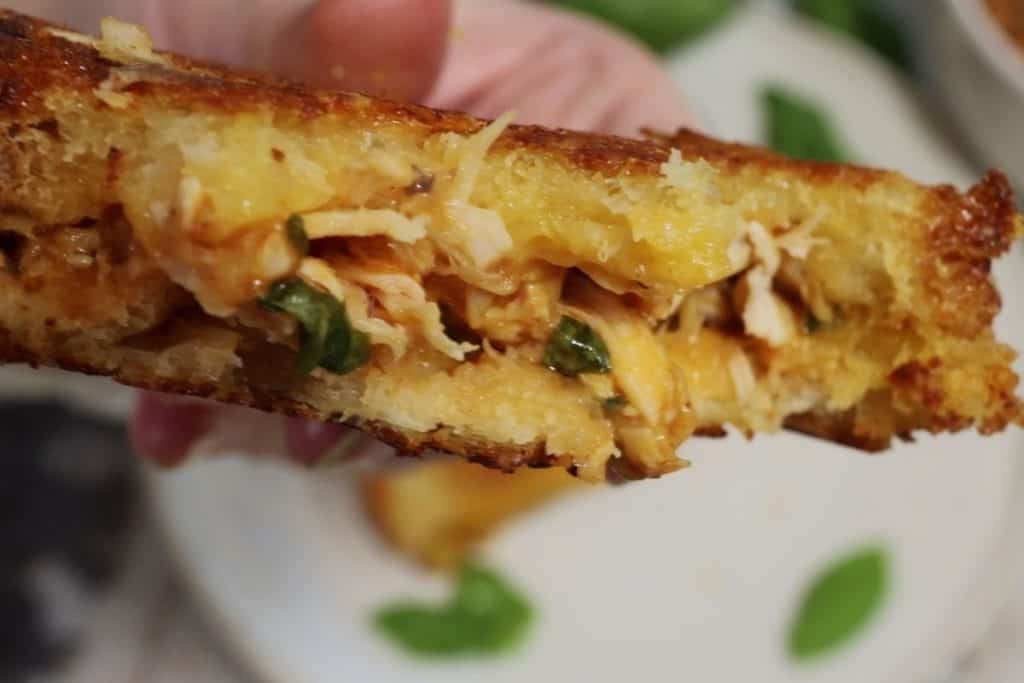 taking a bite of the bbq chicken panini with cheddar and basil