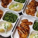 right side view of four easy meal prep bento boxes with easy meal prep - four bento boxes with close up look at one bento box with Grilled BBQ chicken thighs with potato & asparagus