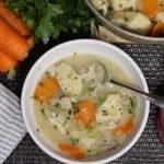 one bowl of chicken and dumplings soup with pot in background