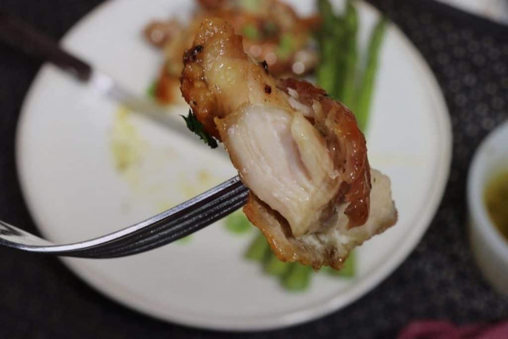 one forkful of crispy chicken thighs with honey garlic sauce