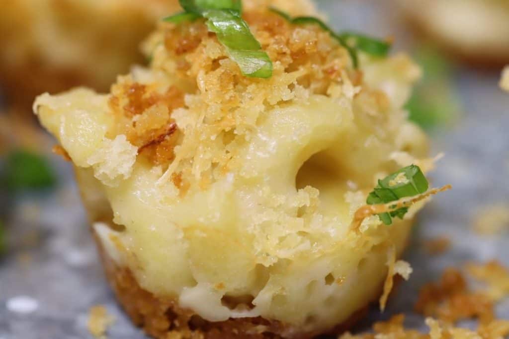 close up of one mac & cheese mini muffin topped with panko crumbs and scallions