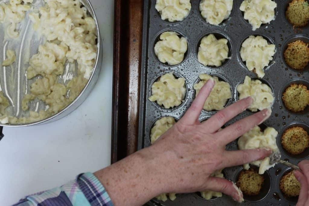 spooning mac & cheese into muffin tins