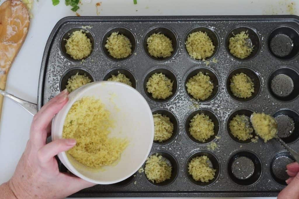 filling mini muffin tins with panko, parmesan garlic bread crumbs