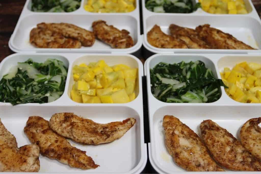 side view of bento box meal prep garam masala tenders with bok choy and squash