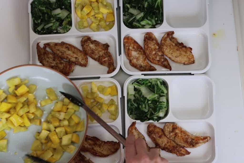 assembling the bento box meal prep containters - garam masala tenders with bok choy and squash