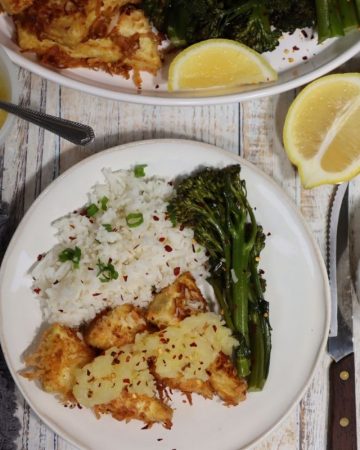 overhead view of one portion of coconut tofu with crushed pineapple, basmati rice, broccolini with platter of food in the background