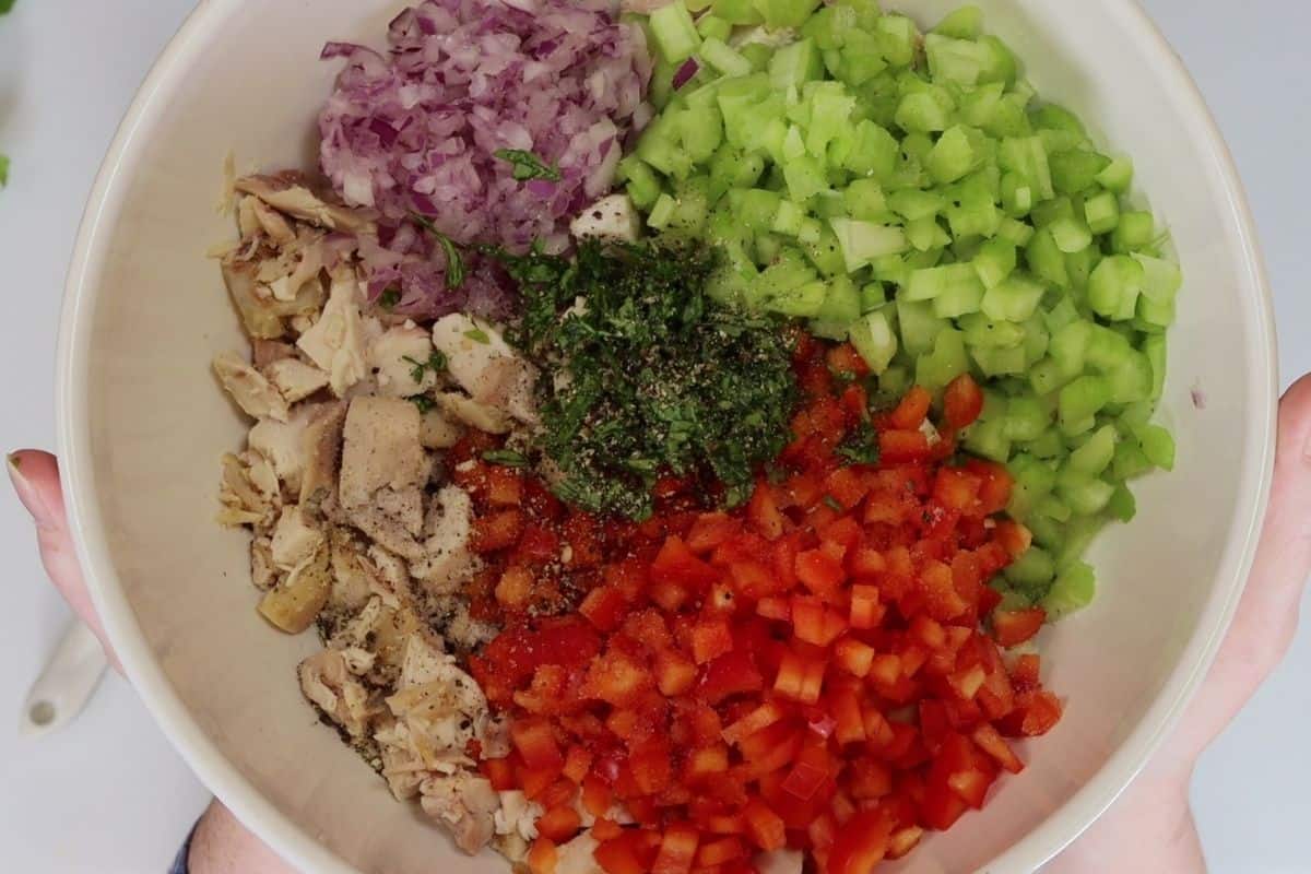 close up of bowl before adding the peanut sauce. bowl contents include chopped rotisserie chicken, celery, red onion, red pepper, cilantro, salt and pepper