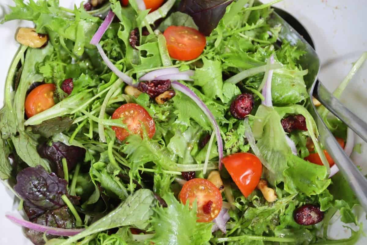 overhead view of a side salad with tomatoes, onions, walnuts and craisins