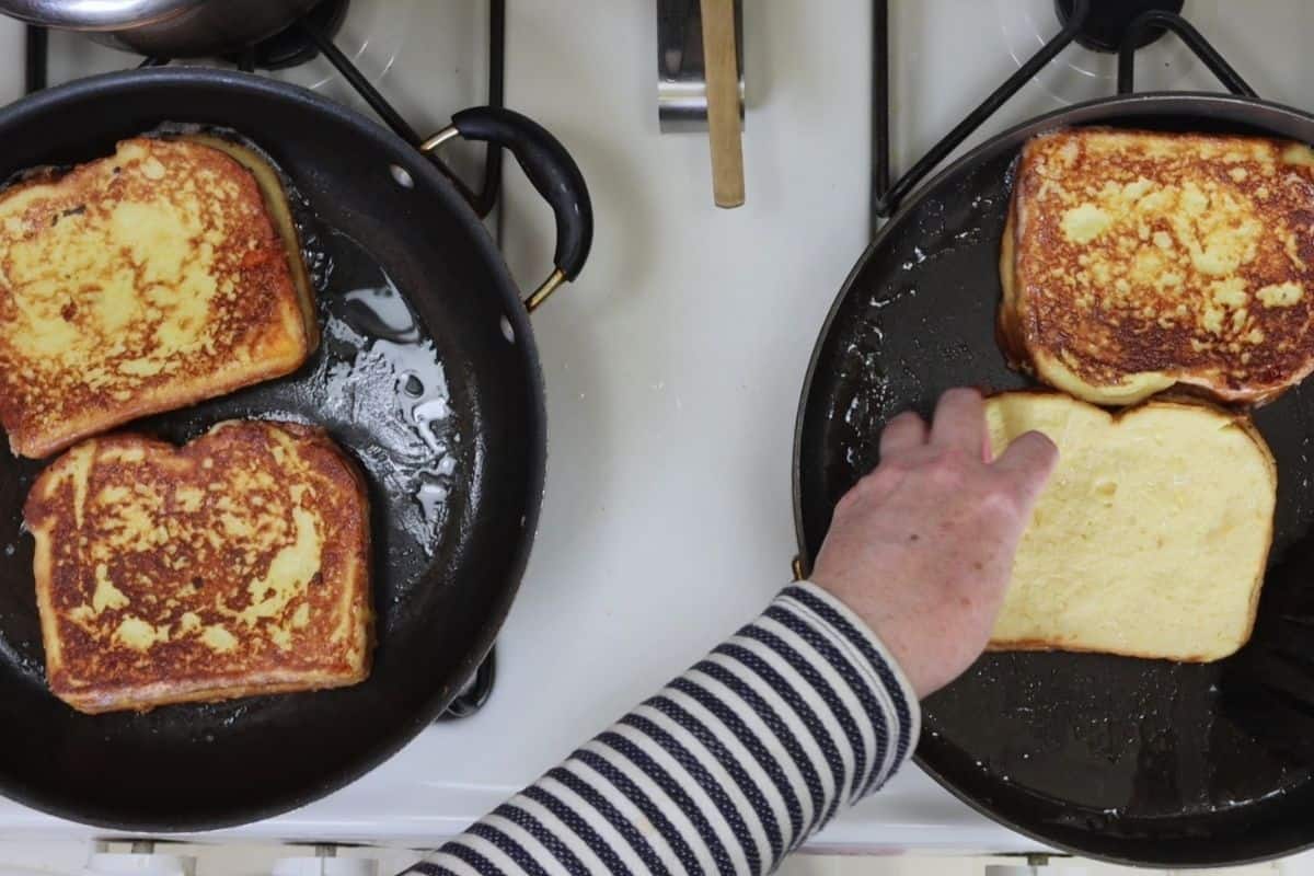 cooking the cheddar stuffed french toast in two pans using canola oil