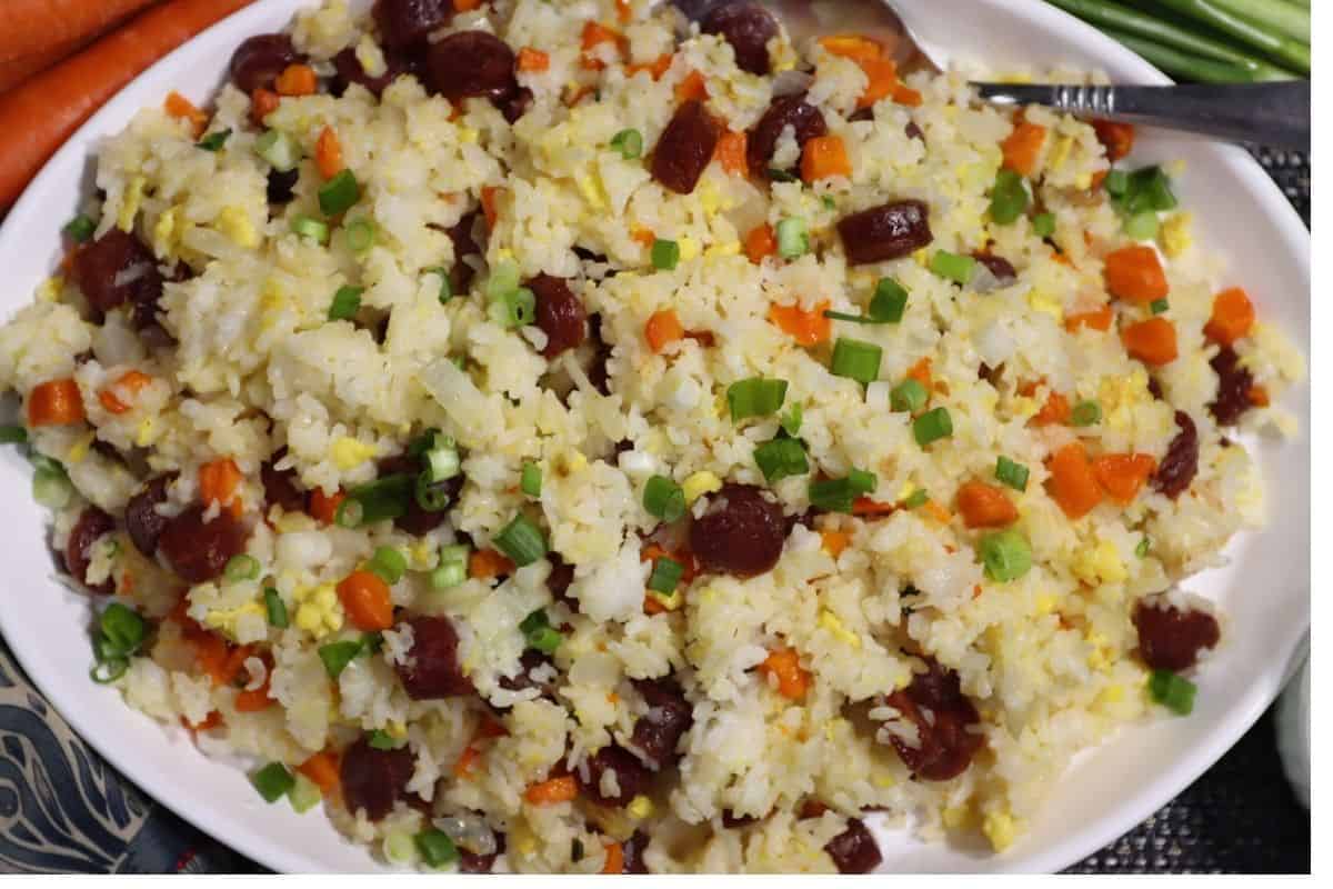overhead view of platter of fried rice with chinese sausage carrots and scallions in background