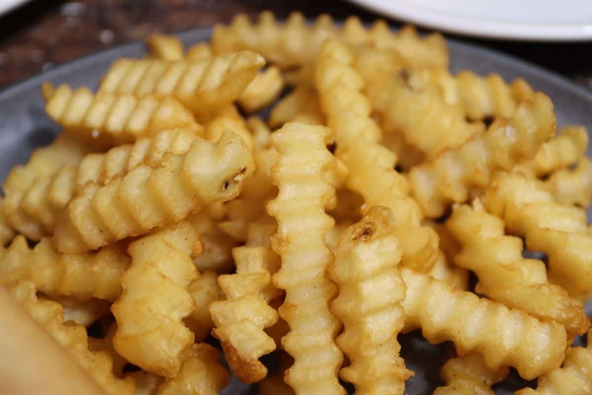 close up of a plate of crinkle cut french fries to serve on the side with your kackle burger