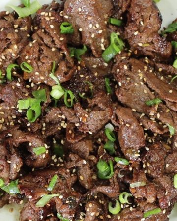 sweet and spicy korean beef bulgogi in a bowl with toasted sesame seeds and scallions
