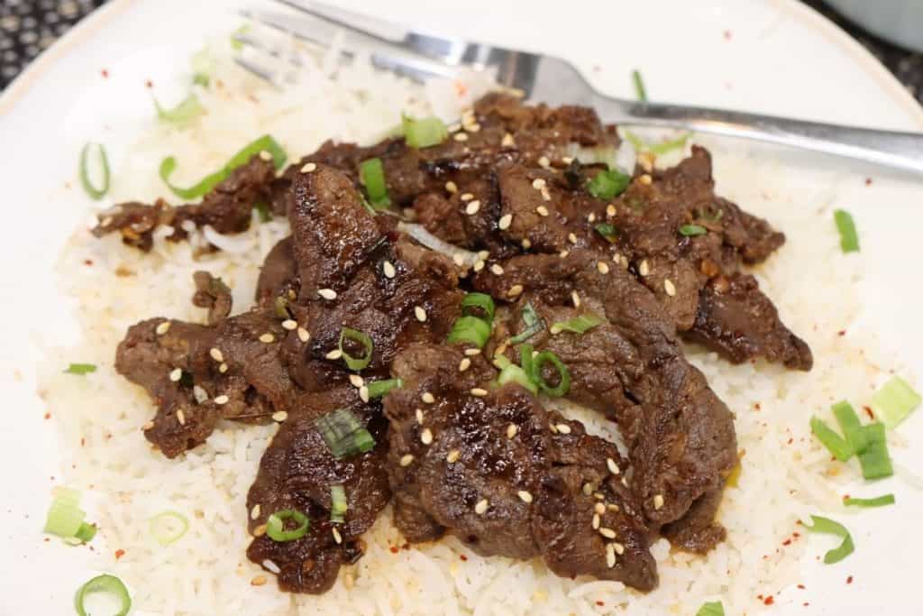 close up view of one plate of korean beef bulgogi on a plate with rice and scallions