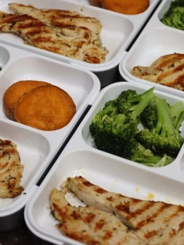 right side view of 4 bento boxes with grilled rosemary chicken broccoli and sweet potatoes