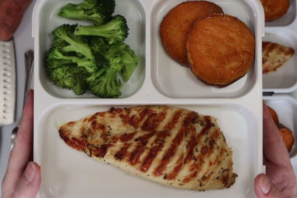close up on one bento box with grilled rosemary chicken broccoli and sweet potatoes