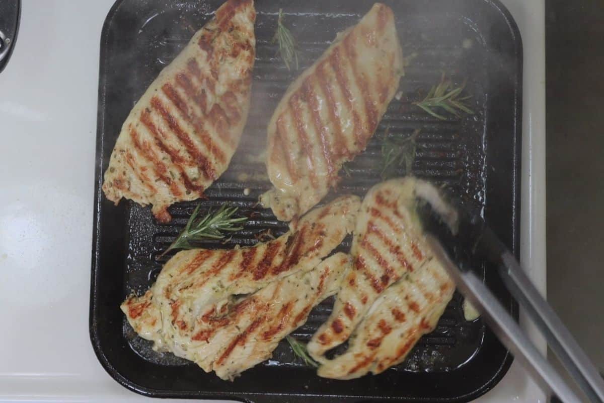 marinated rosemary chicken breast sizzling on a cast iron grill skillet