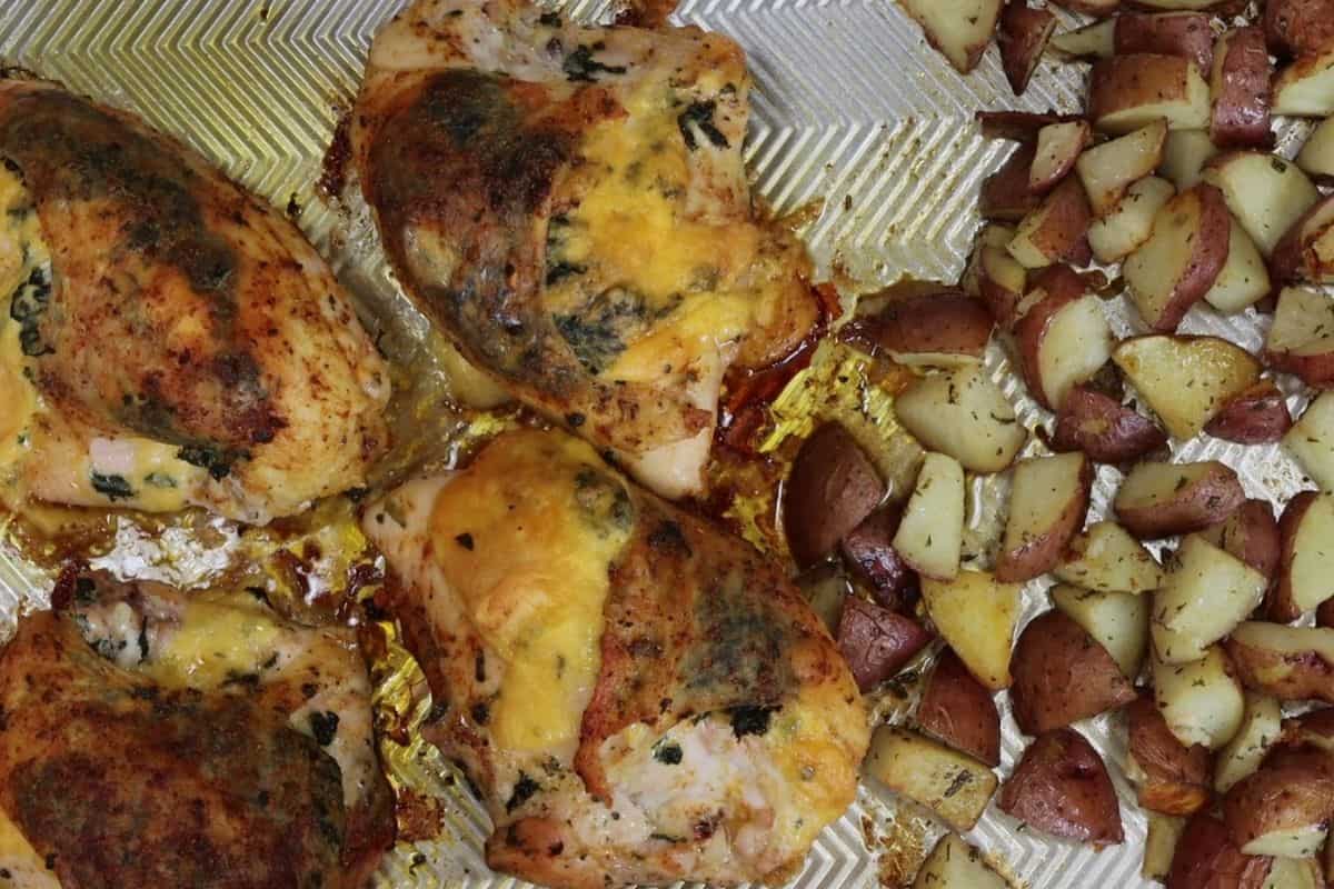 right out of the oven sheet pan dinner with bone-in stuffed chicken breast and rosemary red bliss potatoes