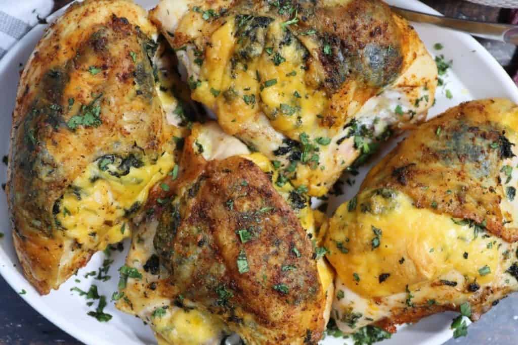 close up look of a platter with bone-in stuffed chicken breast with spinach and gouda garnished with parsley