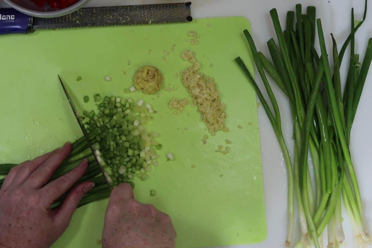 chopping scallions with garlic and ginger on the side
