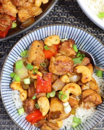 overhead view of one portion of cashew chicken stir fry with a serving plate and basmati rice in the background
