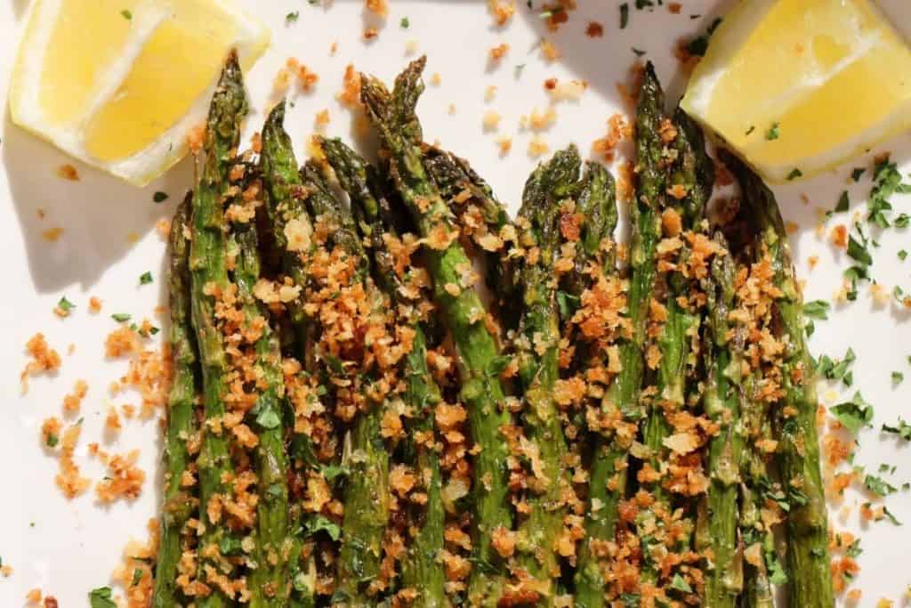 beautiful spring asparagus on a platter in the sunlight topped with lemony breadcrumbs