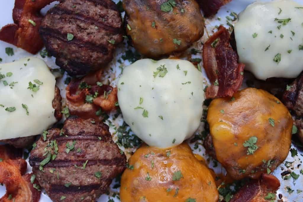 backyard bbq overhead view of bacon stuffed cheeseburgers on a platter garished with bacon chunks and cilantro