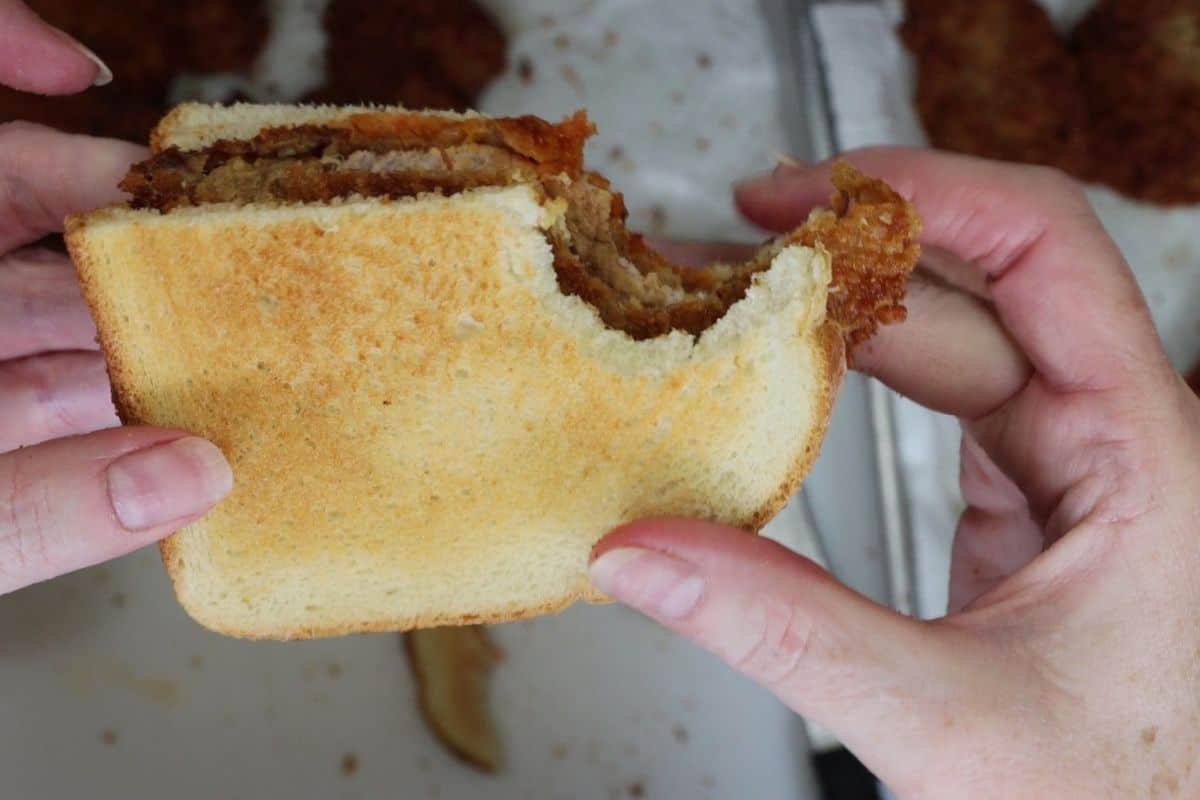 one bite taken out of anthony bourdain's macau-style pork chop sandwich