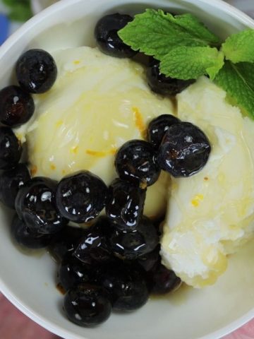 vanilla ice cream topped with blueberries, orange zest and honey mixture and garnished with mint leaves