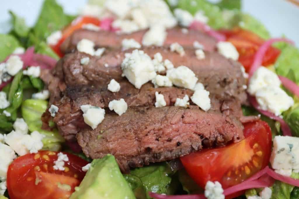 closer look at steak salad with pickled red onions and bleu cheese as well as campari tomatoes, avocado chunks and homemade balsamic vinaigrette