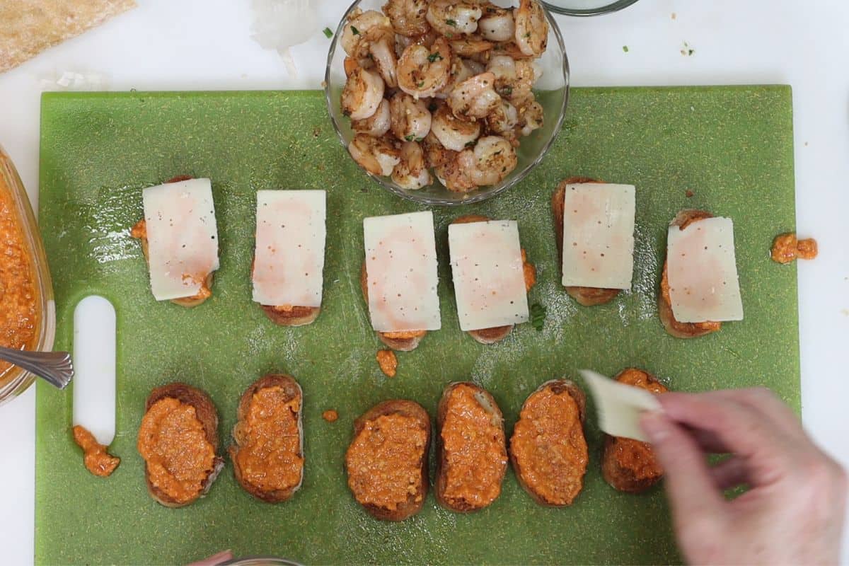 after the romesco sauce is spread on place a slice of shaved parmesan on each crostini