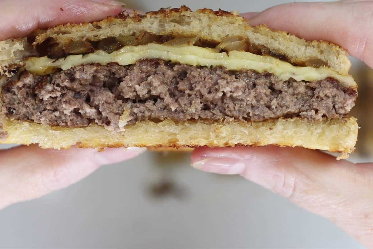 close up look of crunchy cheesy patty melt on grilled sourdough cut in half