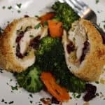 overview of one portion of cranberry brie stuffed chicken with broccoli and carrots and garnished with parsley