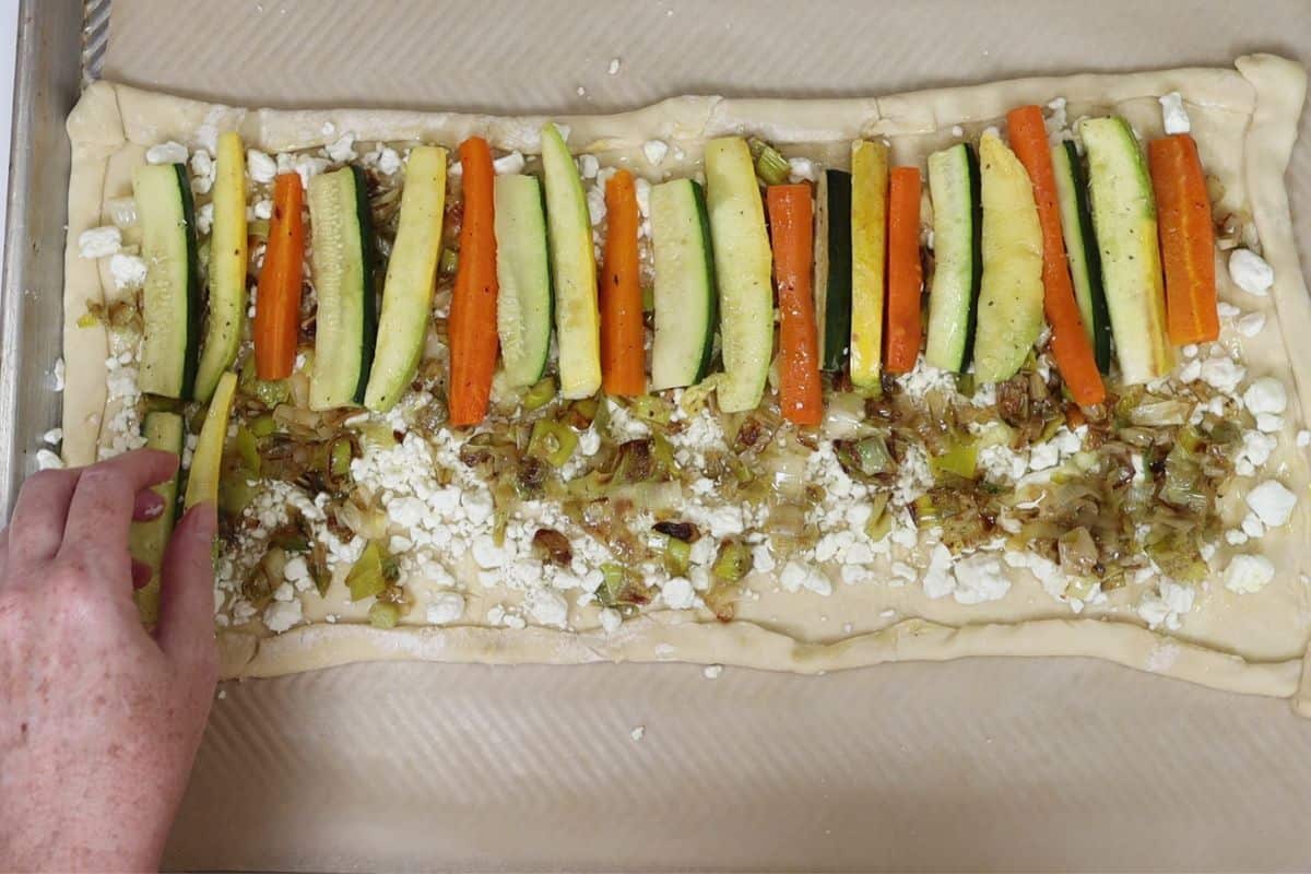 assembling the roasted veggie tart. lay out your veggie sticks on top of the goat cheese and sauteed leeks.