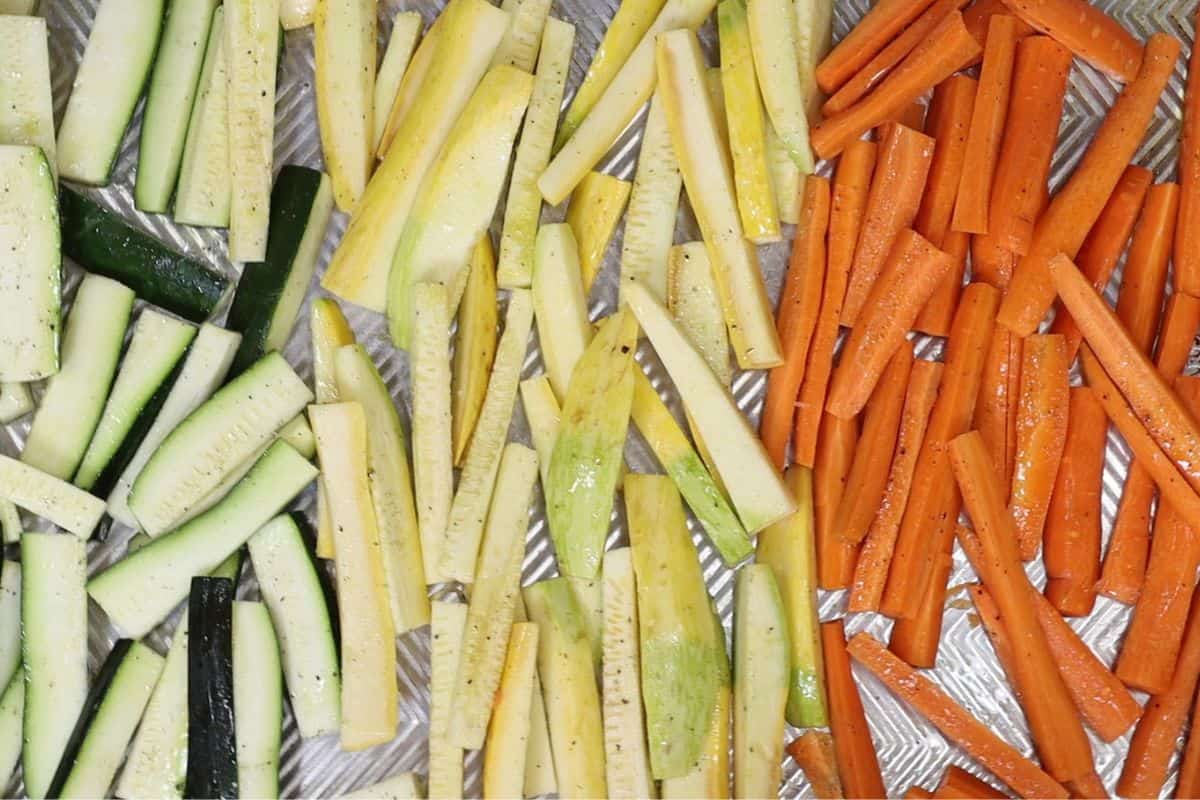 zucchini summer squash and carrots cut into sticks with olive oil, salt and pepper. Getting ready to roast in oven.
