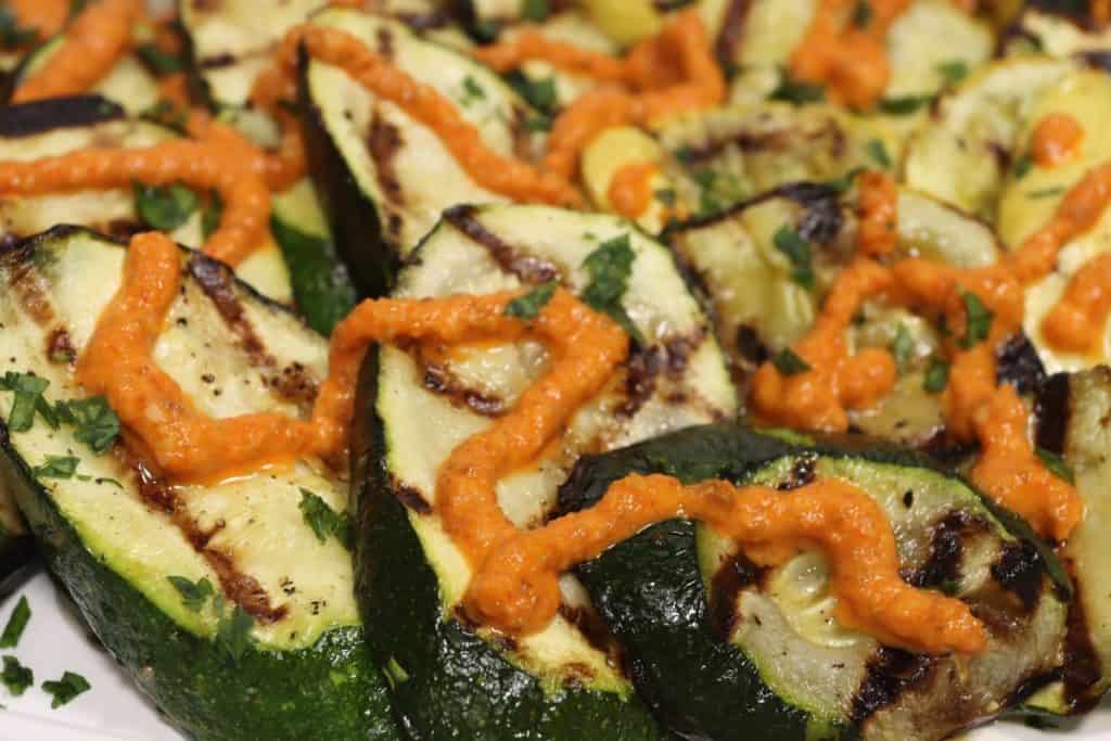 a closer look at the grilled zucchini side of the veggie platter drizzled with romesco sauce