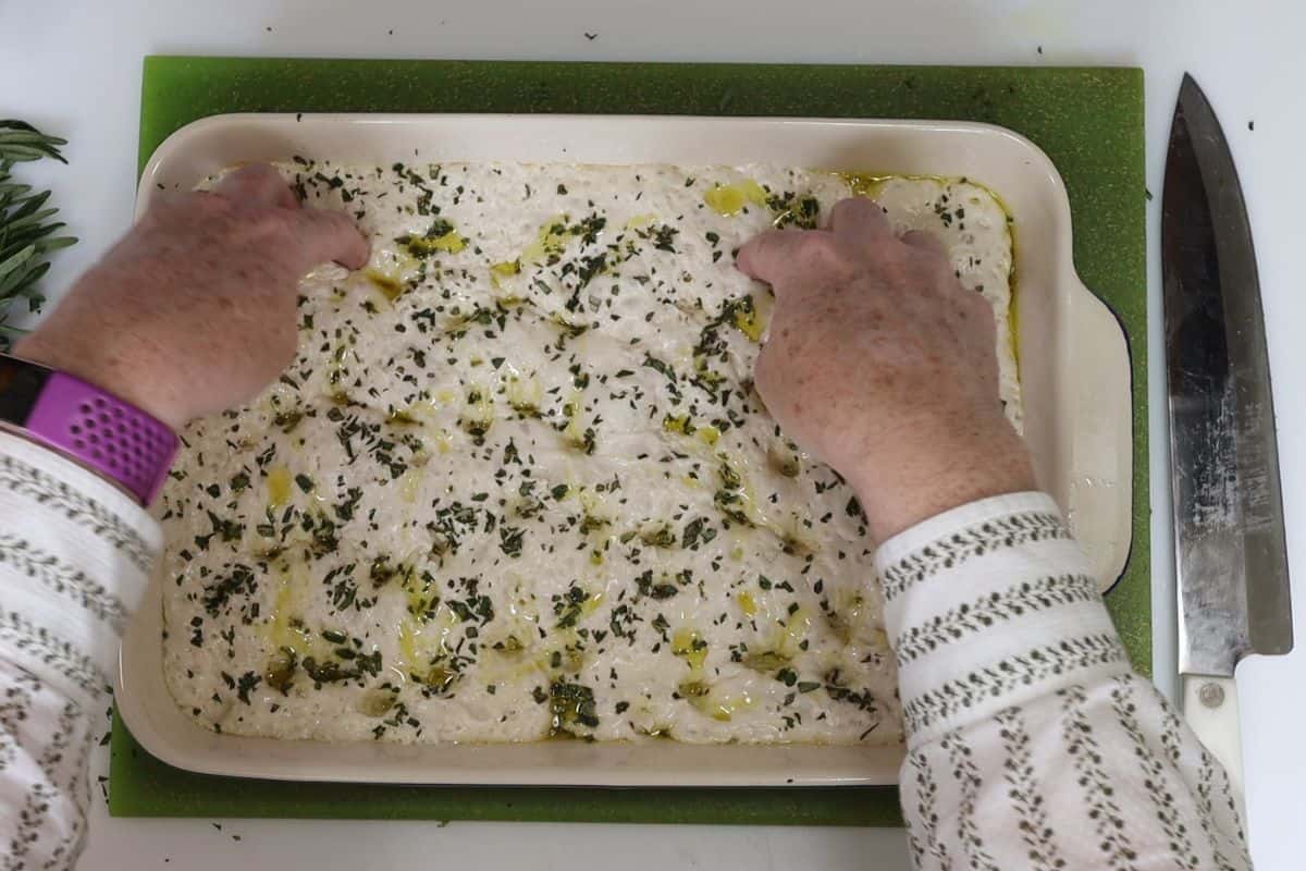 11-steps to making focaccia bread-add olive oil, rosemary and flaky salt top and dimple with fingers