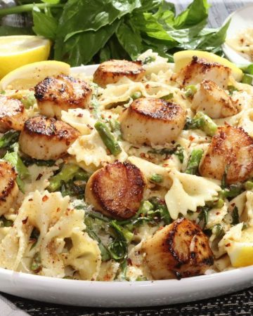 side view of platter of pan seared sea scallops with basil brown butter, asparagus and pasta - serve all the extras on the side