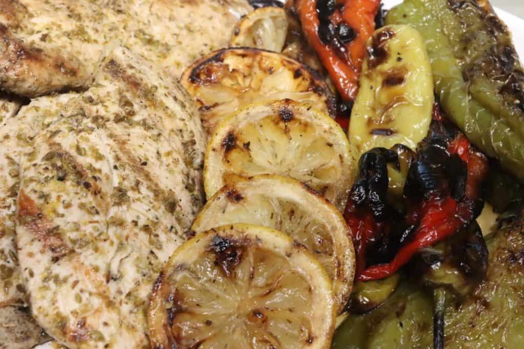 a closer look at small platter of grilled lemon oregano chicken with charred lemons and clark farm peppers
