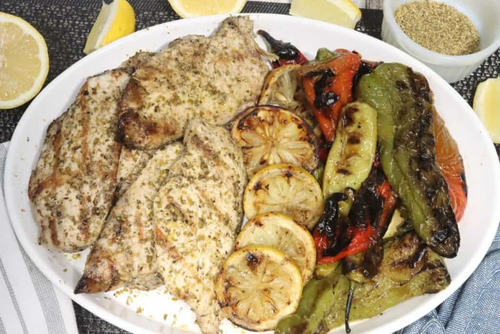 overhead view of small platter with grilled lemon oregano chicken and charred clark farm peppers