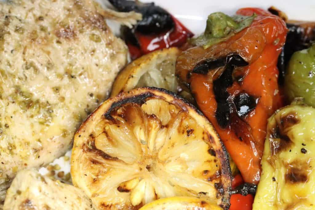close up look at grilled lemon oregano chicken with charred lemons and clark farm peppers
