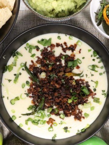 super bowl white queso dip with crispy crumbled beef: overhead view of queso dip with all the fixins including tortilla chips, crumbled beef, guacamole, chilis, scallions and salsa