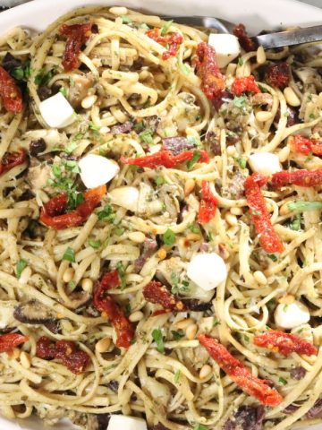 Pesto Pasta with Olives: overhead view of family-style platter of linguine with pesto, olives, shiitakes, artichokes, mozzarella, toasted pine nuts and sun dreid tomatoes